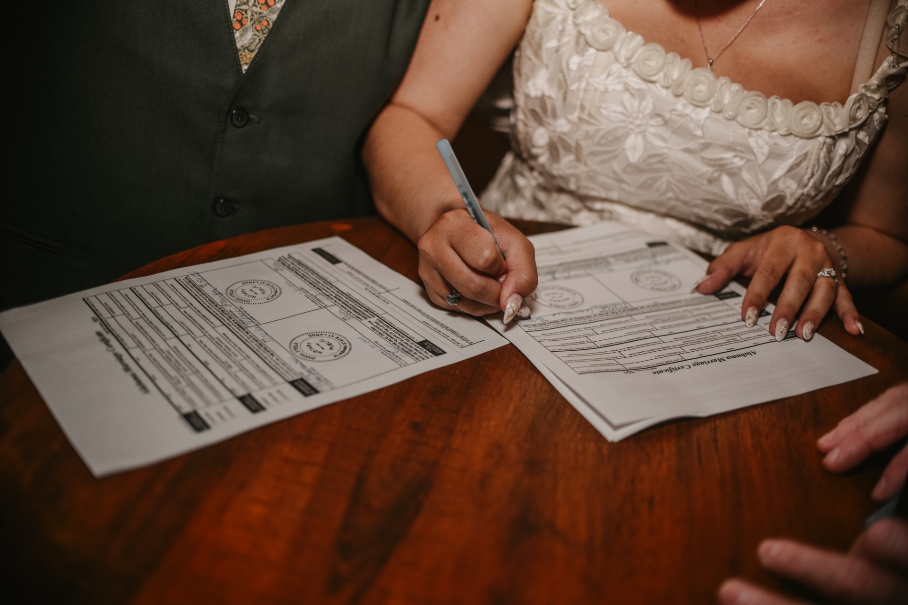 Bride and groom signing their Alabama marriage certificate together