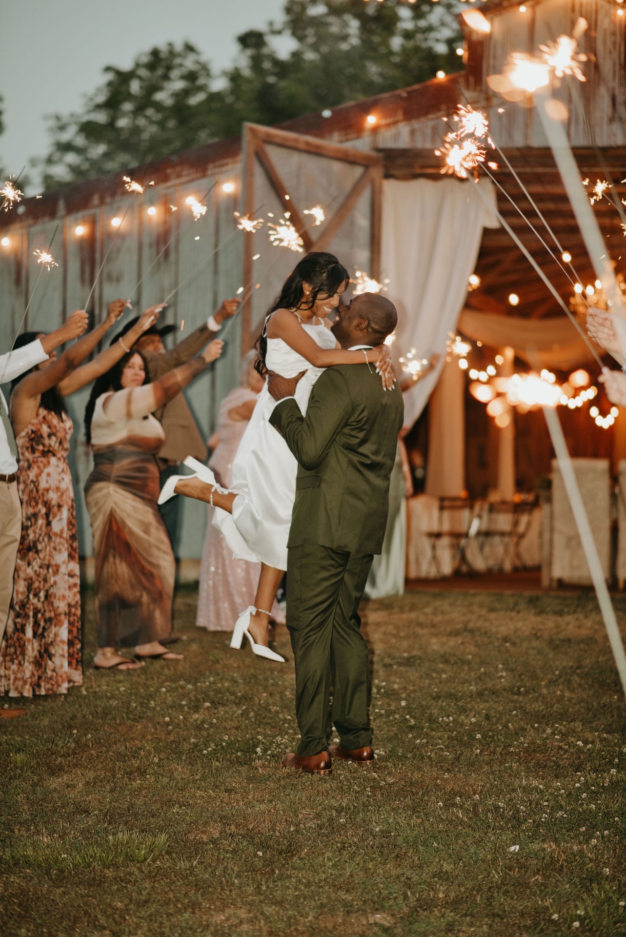 Bride and groom sharing a joyful sparkler exit embrace outside their reception venue